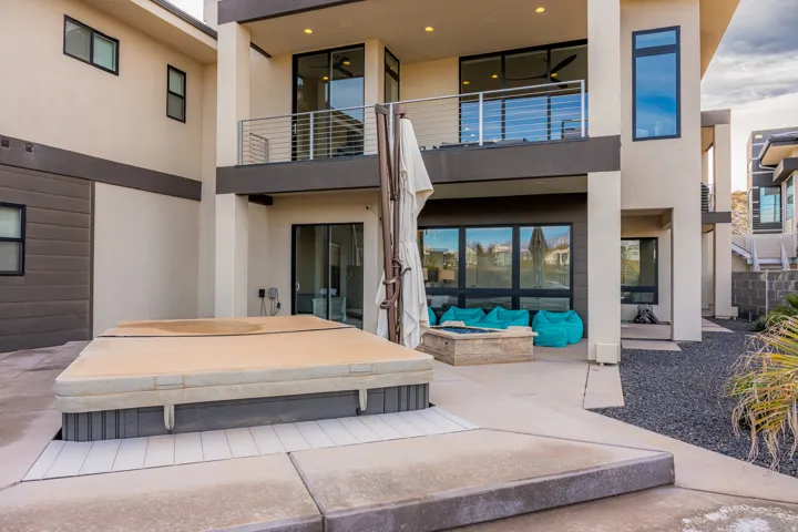 Expansive patio featuring a built-in fire pit, covered spa area, and rock landscaping
