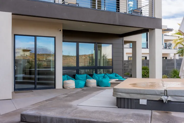 Expansive concrete patio with a built-in hot tub, ground-level windows, and sliding glass doors