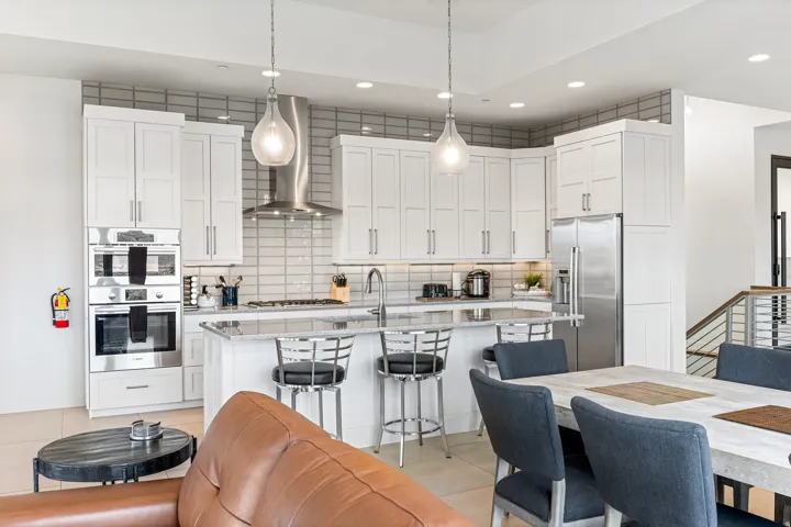 Modern kitchen featuring white shaker cabinetry, stainless steel appliances, a center island with counter seating, and pendant lighting