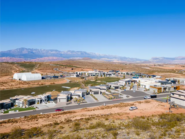 Expansive development with numerous contemporary residences, mountain backdrop, and scattered green landscaping