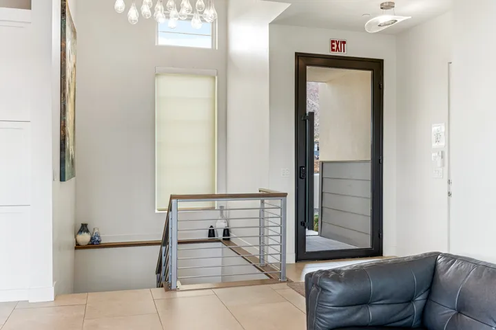 Tile flooring, modern cable railing, contemporary chandelier, transom window, and a full-light entry door