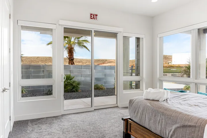 Multiple large windows, glass sliding door, light gray carpet flooring, white walls, recessed ceiling lighting