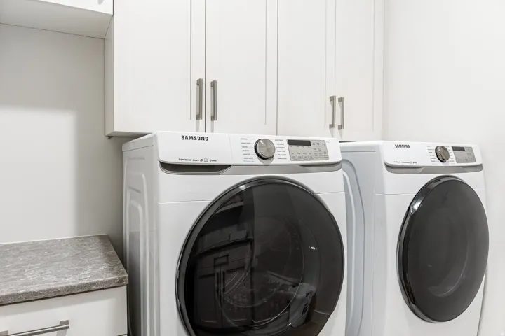 White shaker-style cabinetry with brushed nickel hardware, light-toned countertop, and white walls