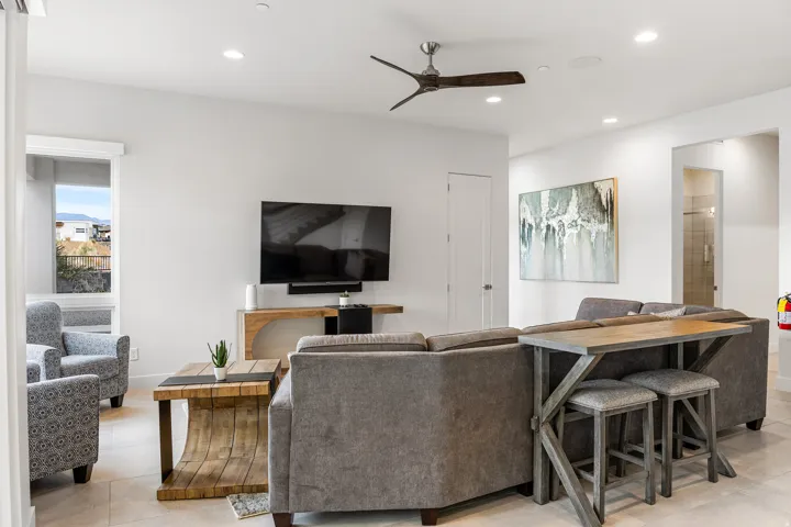 Spacious living area featuring neutral wall tones, recessed lighting, a ceiling fan, a large window, and tile flooring