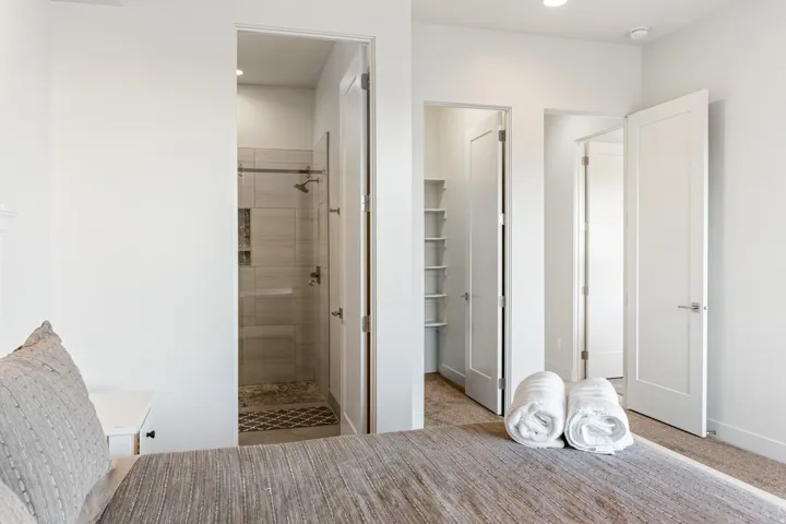 Shower enclosure with glass paneling, tiled walls, and pebble flooring