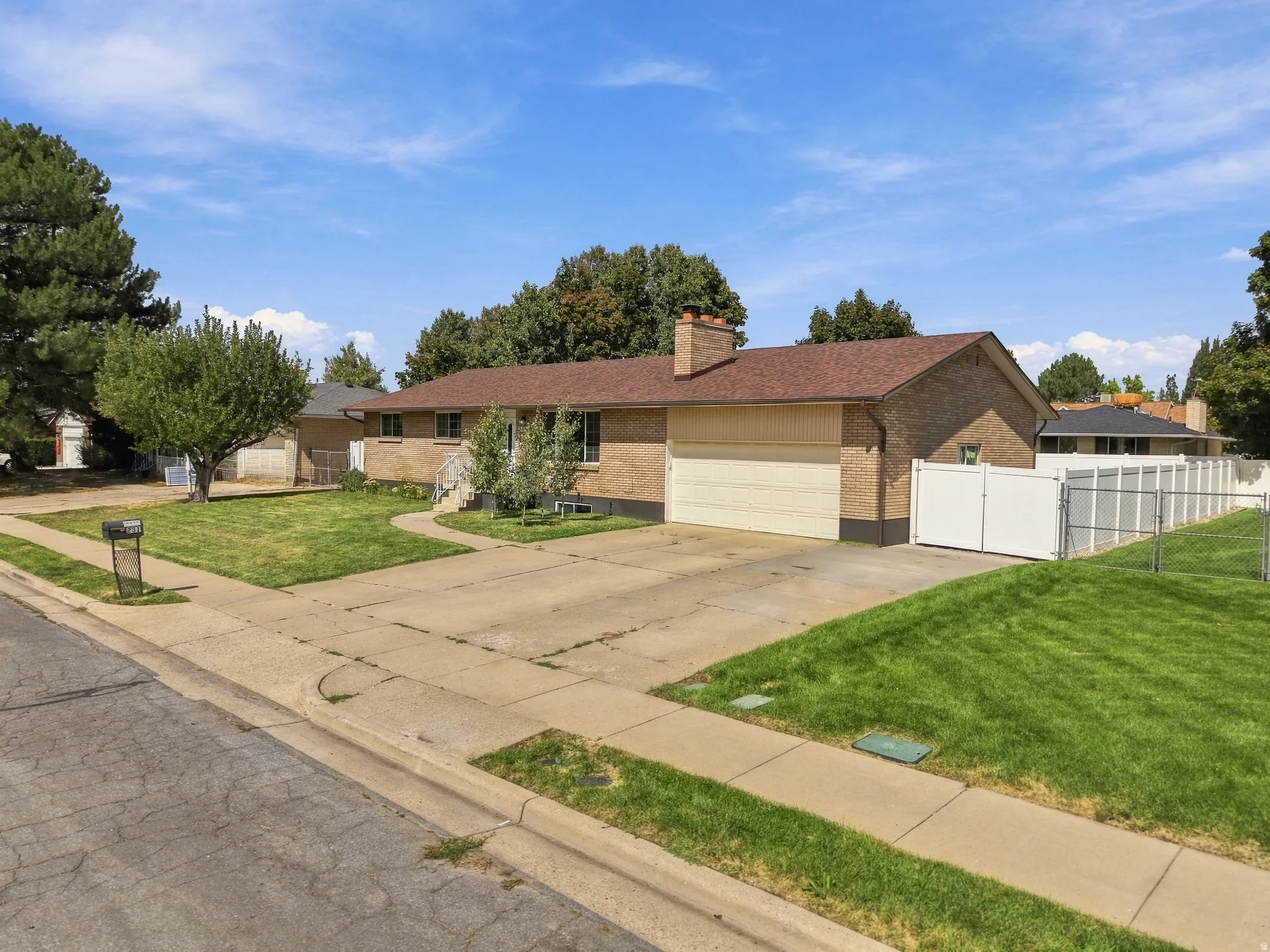 Brick exterior with a brown shingle roof, attached garage, concrete driveway, and front lawn