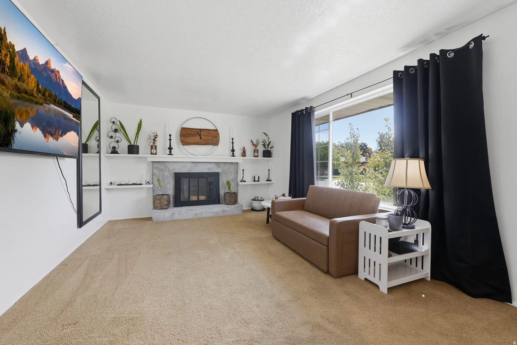 Living area with carpeted flooring, a fireplace featuring a stone surround, built-in shelving, and a large sliding glass door