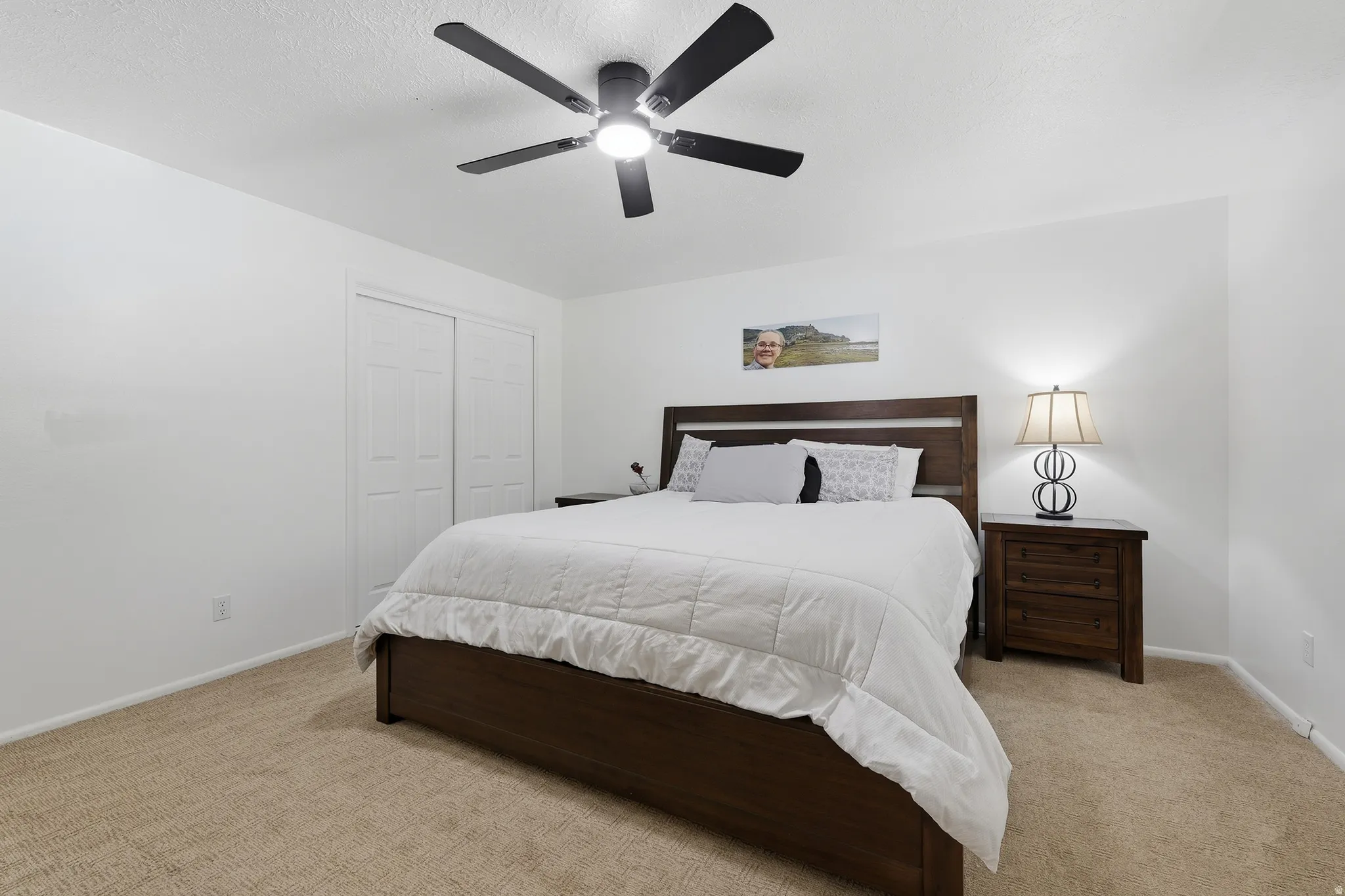 Carpeted flooring, white walls, and a ceiling fan with integrated lighting
