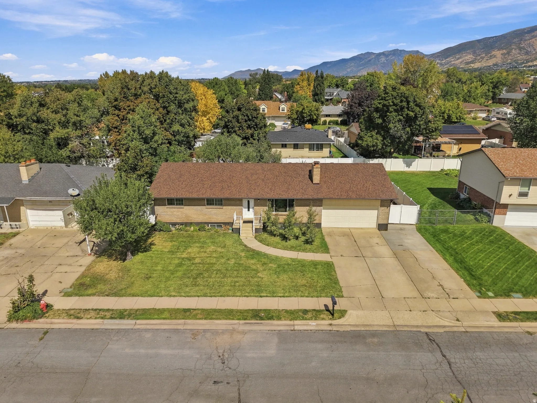 Brick single-story residence with a brown shingle roof, attached two-car garage, front lawn, and paved driveway