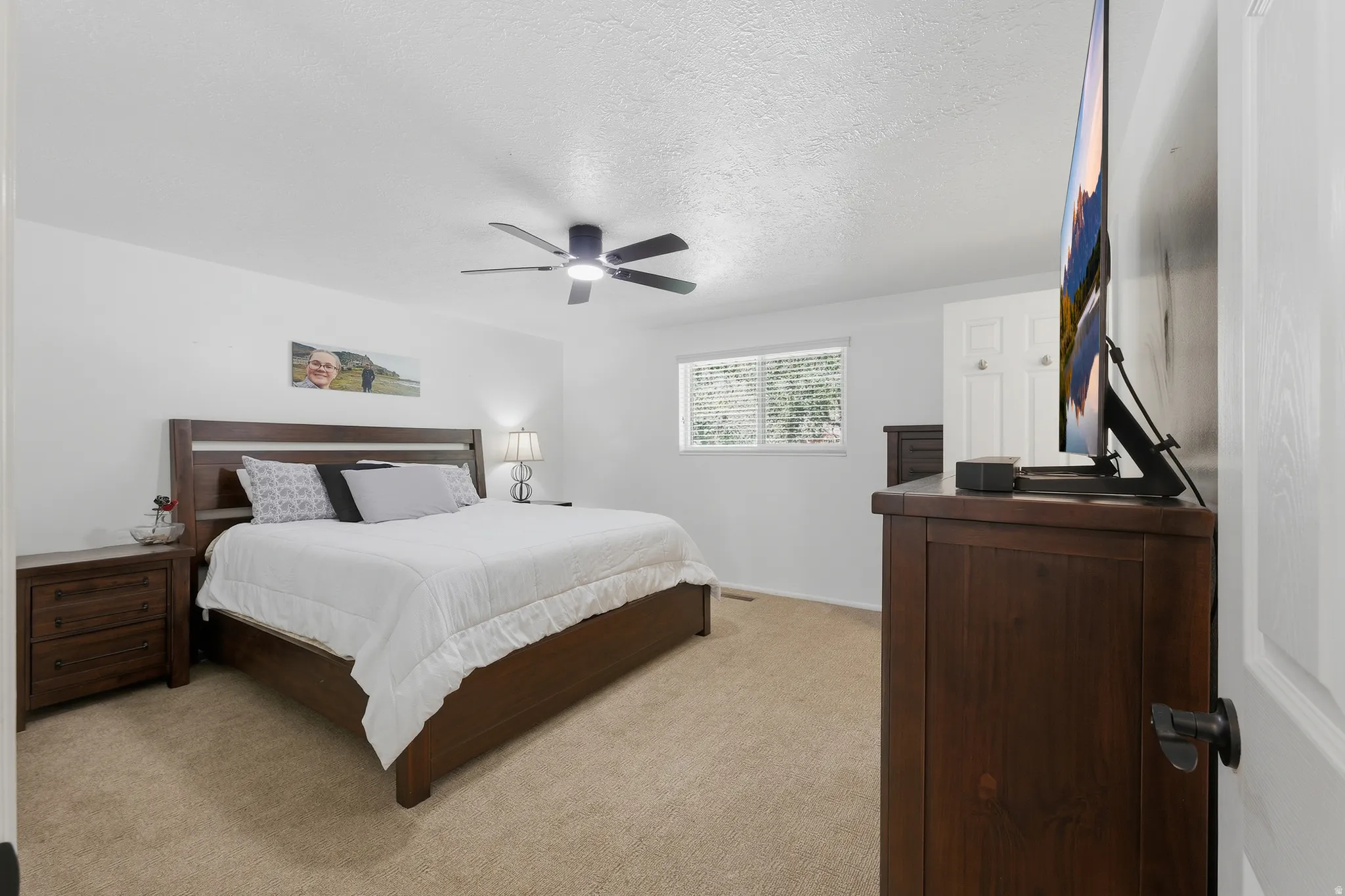 Carpeted room with a ceiling fan, recessed window, and white walls