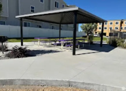 Covered outdoor seating area with concrete paving and integrated picnic tables