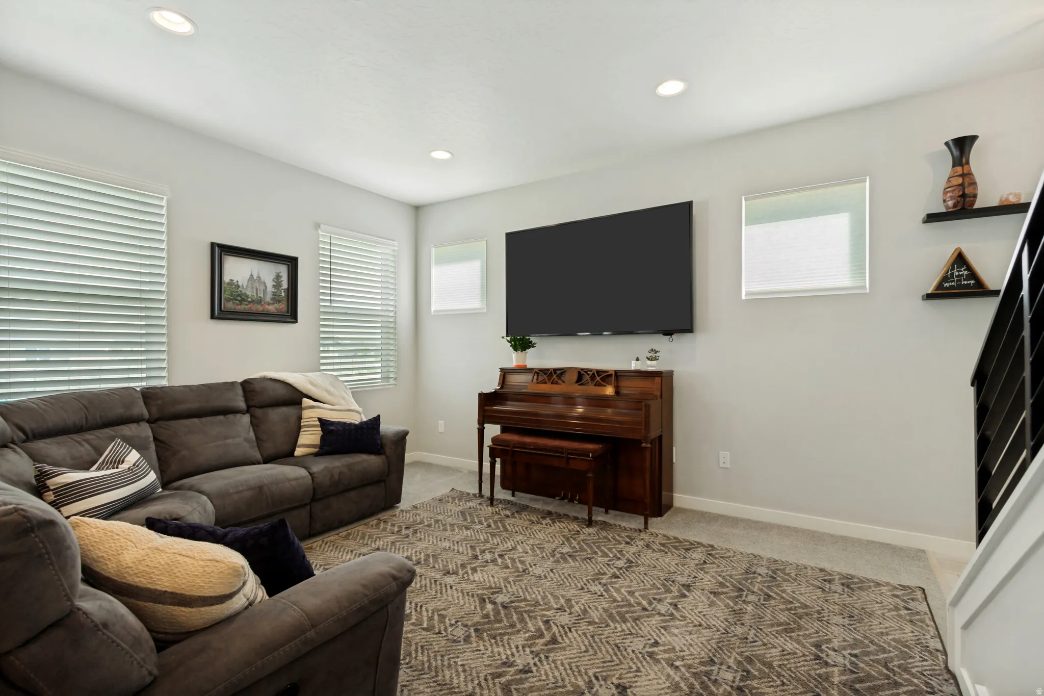 Recessed lighting, multiple windows with blinds, wall-mounted television, and a carpeted floor