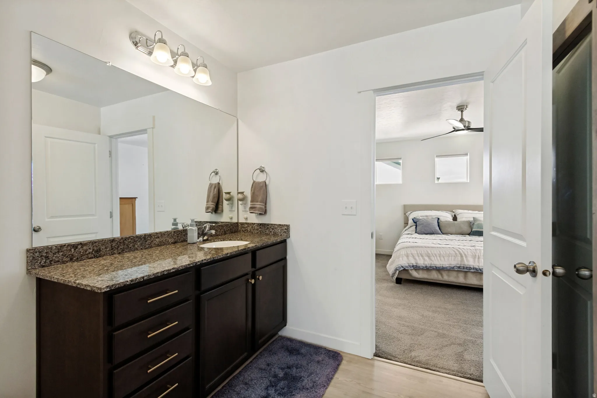 Vanity with brown-toned cabinetry, a built-in sink, and a speckled countertop