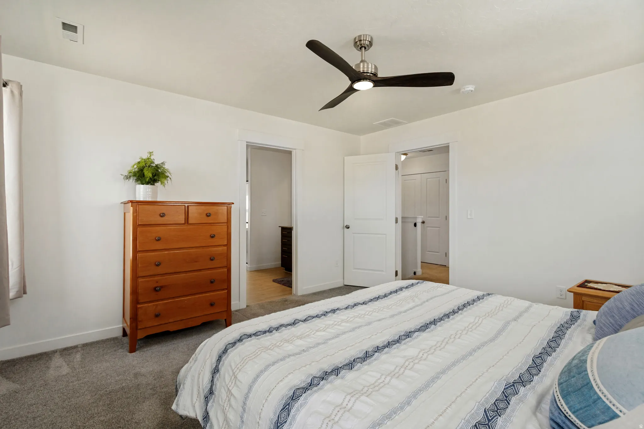 White walls, gray carpet flooring, and a contemporary ceiling fan with integrated lighting