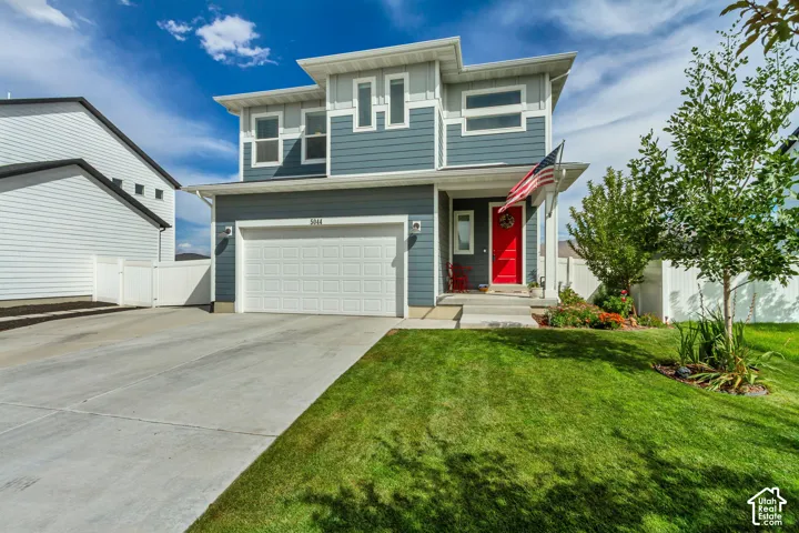 Modern exterior with multi-toned siding, attached two-car garage, concrete driveway, and a red entry door