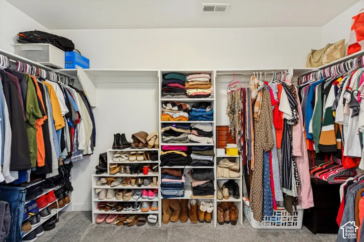 Custom closet organization system with ample hanging rods, built-in shelving, and shoe storage