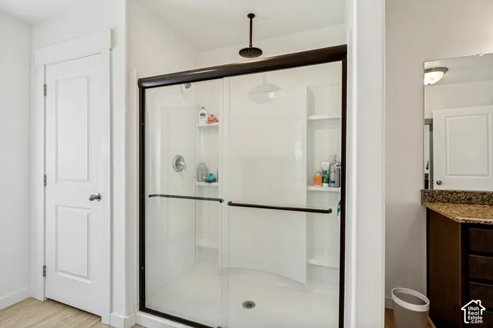 Walk-in shower with dark bronze framing and fixtures, built-in shelving, and a rain showerhead