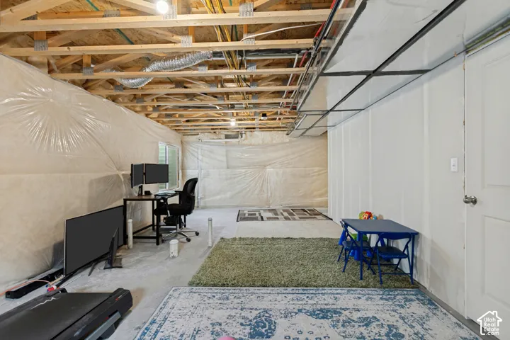 Unfinished basement offering flexible potential space, exposed wooden ceiling joists, visible ductwork, and a built-in wall with a door