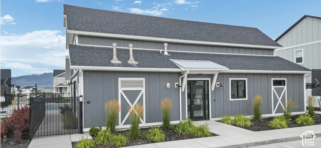 Board and batten exterior with a dark shingle roof, featuring a covered entry and decorative barn door accents