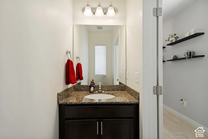 Vanity with a granite-finish countertop, undermount sink, and dark wood-finish cabinetry