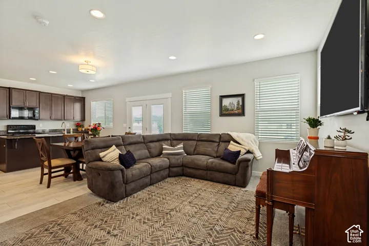 Open concept living area featuring recessed lighting, a kitchen with dark wood-finish cabinetry, light wood-finish flooring, and French doors