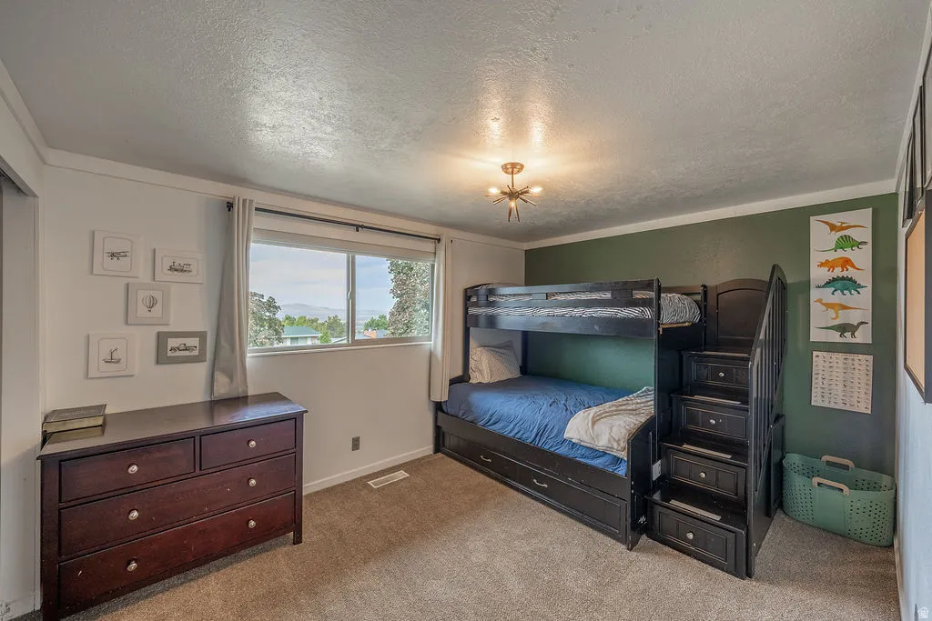 Carpeted flooring, window with exterior scenery, crown molding, and a modern ceiling light fixture