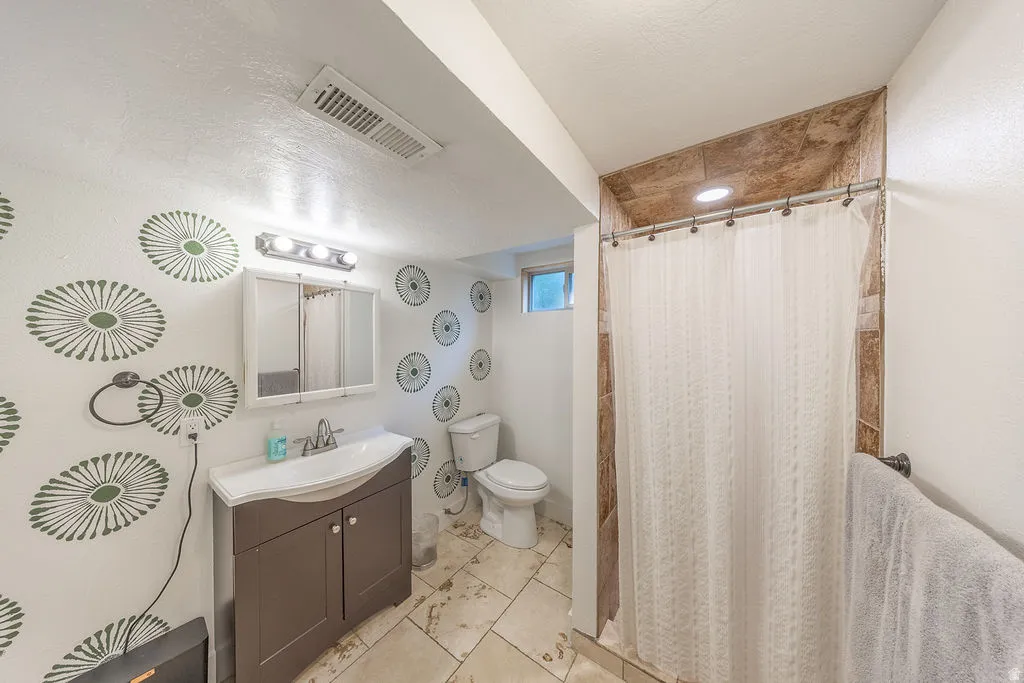 Bathroom featuring a single vanity with storage, a tiled shower surround, recessed lighting, and a window