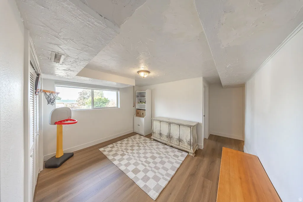 Recessed window offering natural light, wood-finish flooring, built-in shelving, and overhead lighting