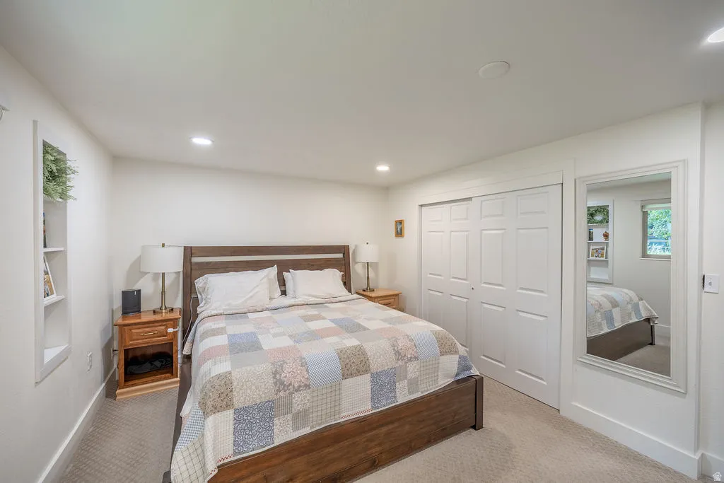 Recessed lighting, built-in shelving, carpet flooring, and a sliding closet door