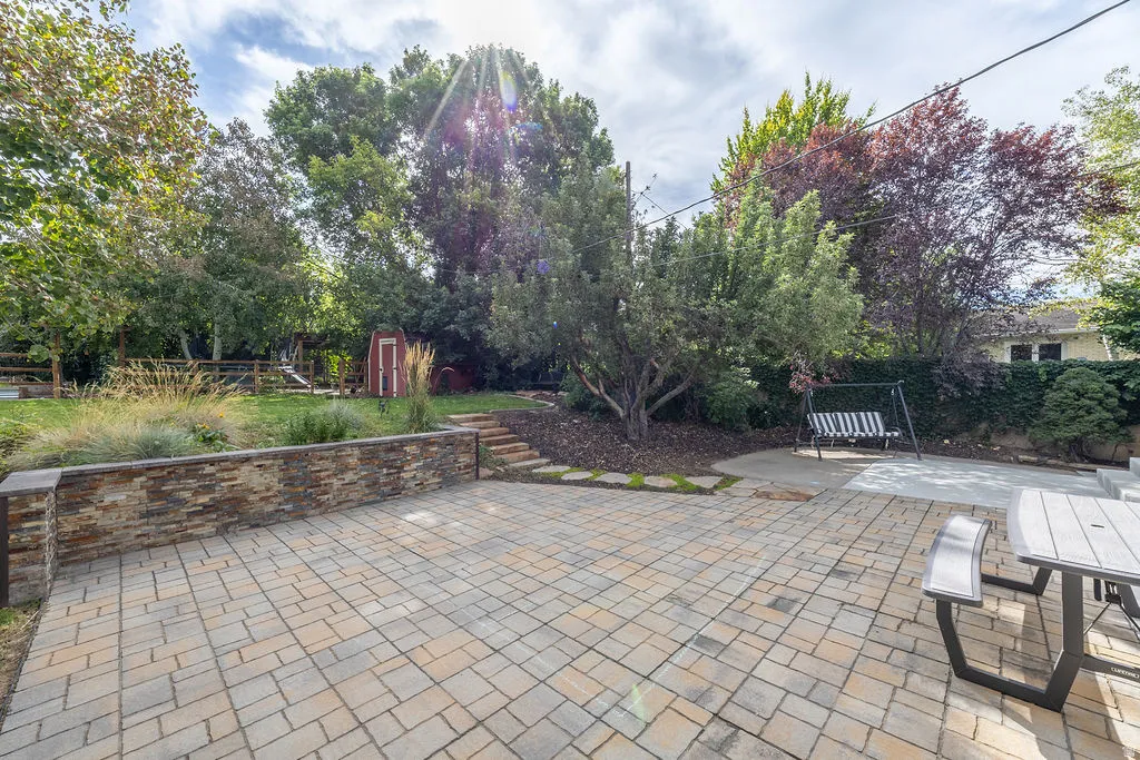 Expansive hardscaped patio featuring interlocking pavers and a stone-clad retaining wall
