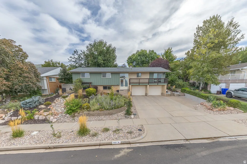 Two-story residence featuring a split-level design, multiple attached garages, and a prominent balcony
