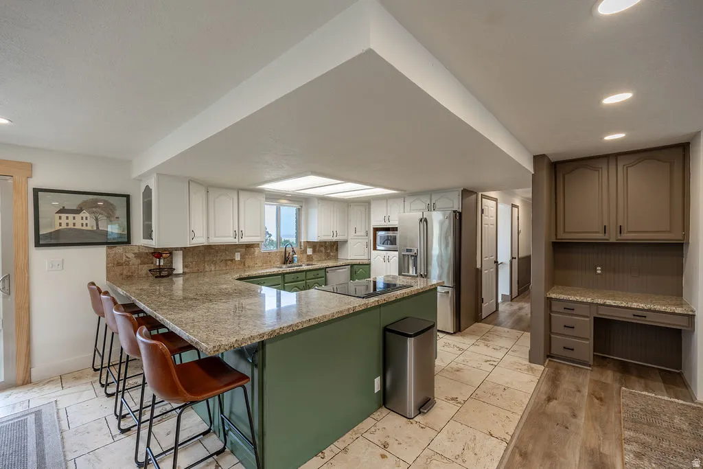Kitchen featuring a large island with stone countertop, tile flooring, recessed lighting, and white upper cabinetry
