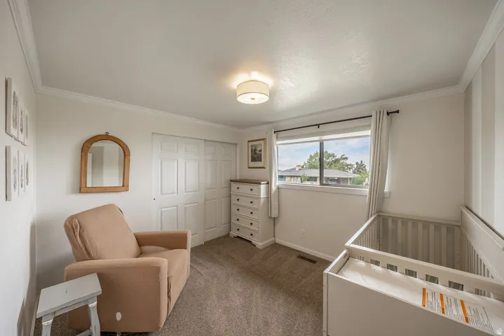 Carpeted room featuring a double-paned window, crown molding, a ceiling-mounted light fixture, and a built-in sliding closet