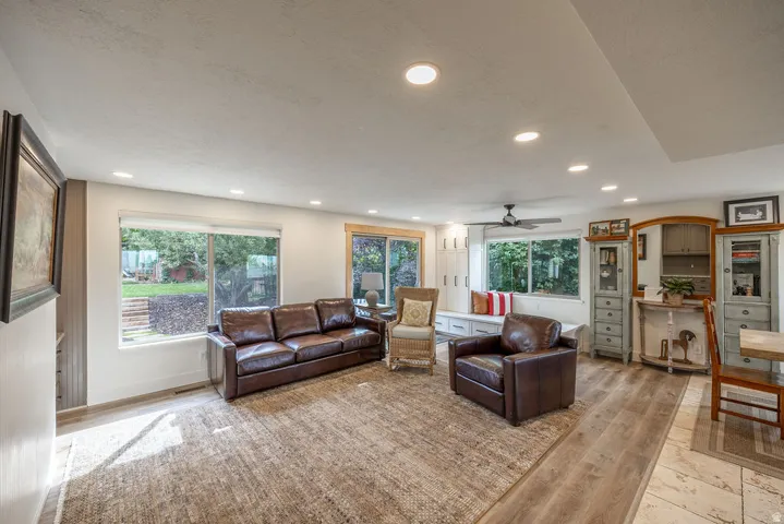 Recessed ceiling lighting, multiple large windows, built-in window seating with storage, a ceiling fan, and mixed wood-finish and tile flooring