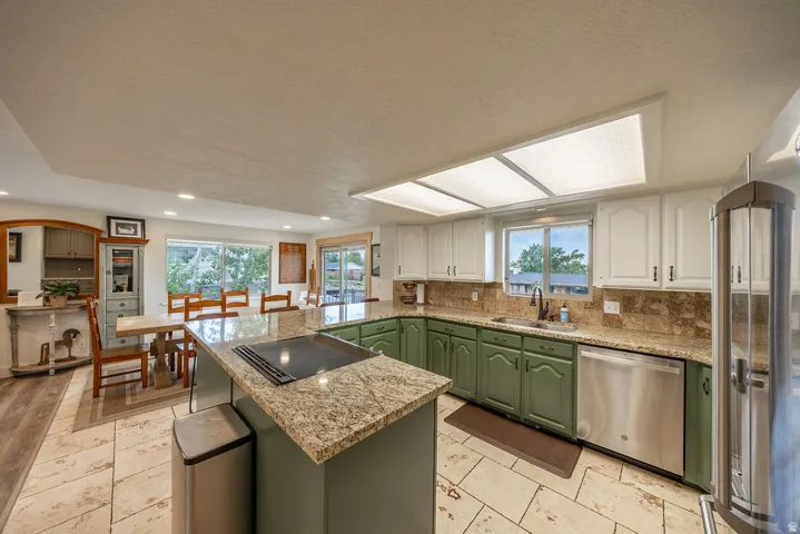 Kitchen featuring a central island with cooktop, granite countertops, and stainless steel appliances