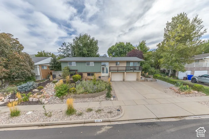 Two-story residence featuring a split-level design, multiple attached garages, and a prominent balcony