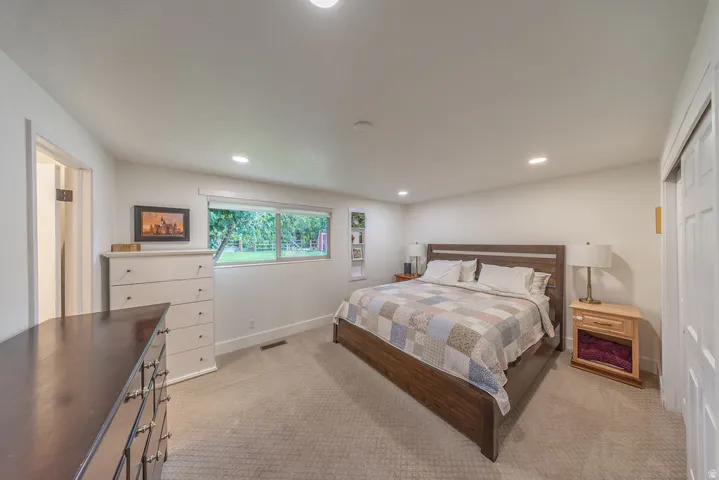 Recessed lighting with a large window, light-toned carpeting, and a sliding closet door