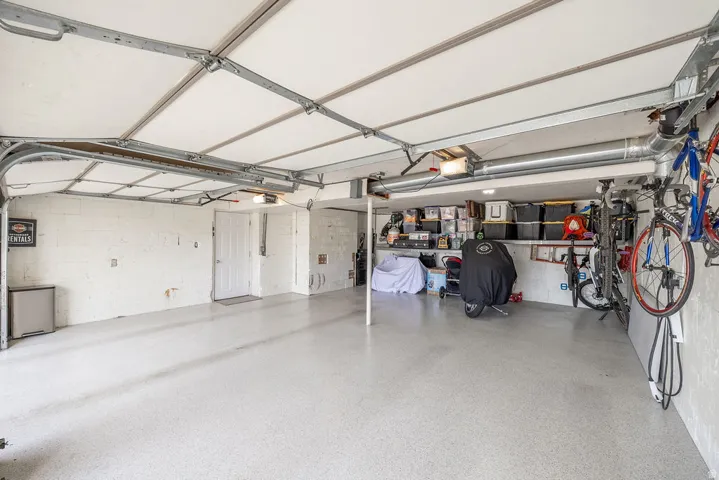 Spacious garage featuring a light-toned finished floor, white painted walls, and overhead lighting