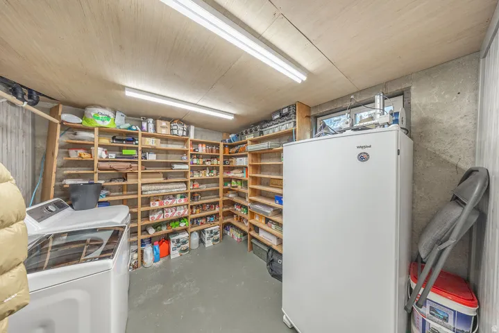 Extensive built-in shelving, concrete walls, overhead fluorescent lighting, and a window