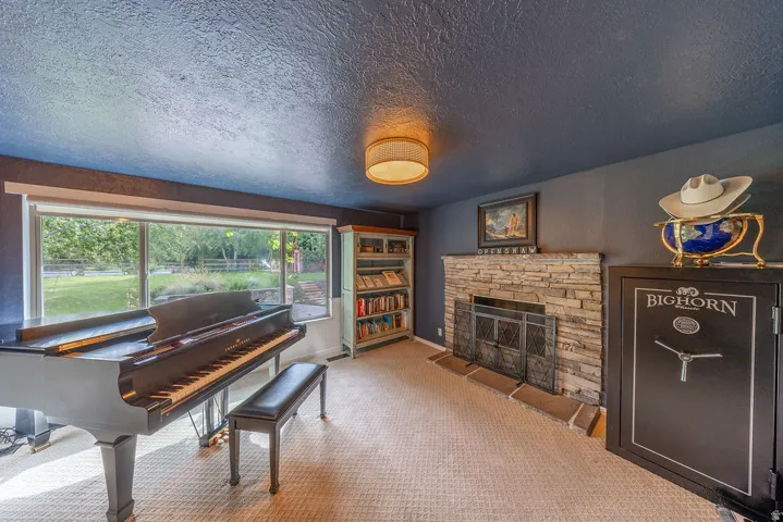 Expansive picture window, stacked stone fireplace with hearth, built-in shelving, textured ceiling, and recessed lighting