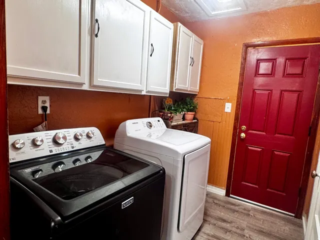 Wood-finish flooring with white upper cabinetry, a paneled door, and a skylight