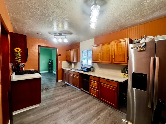 Hardwood cabinetry, light-toned countertops, wood-finish flooring, and recessed lighting