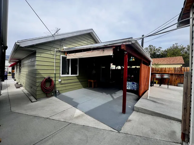 Covered patio area with wood siding, a concrete pad, and a privacy fence