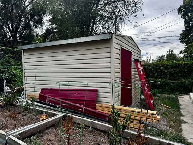 Detached utility shed with horizontal siding and a red door
