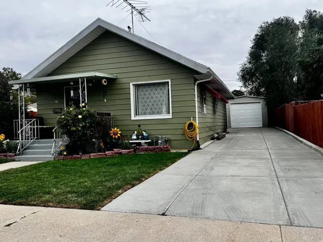 Gable roofline, exterior siding, concrete driveway, detached garage, and front porch with awning
