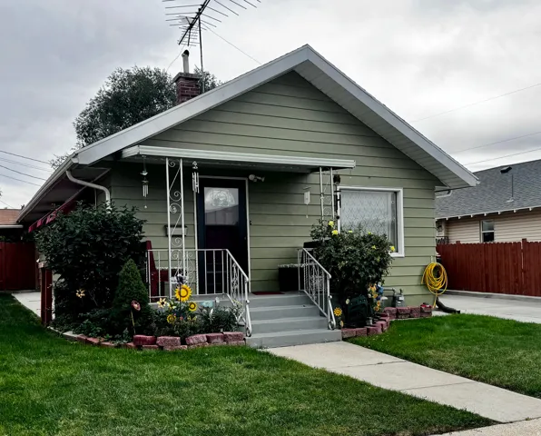 Gable roofline, exterior siding, front entry door with decorative glass, front porch with metal railing, and a concrete walkway
