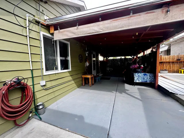 Covered patio area featuring a slatted wood ceiling, string lighting, and direct exterior access