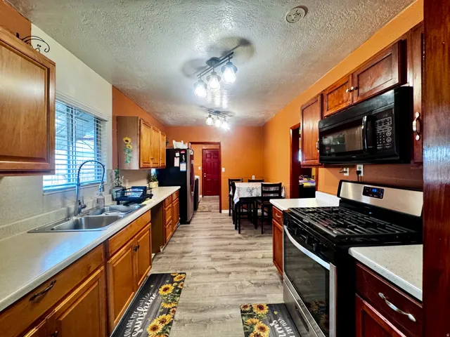 Galley kitchen featuring wood cabinetry, stainless steel range, and wood-finish flooring