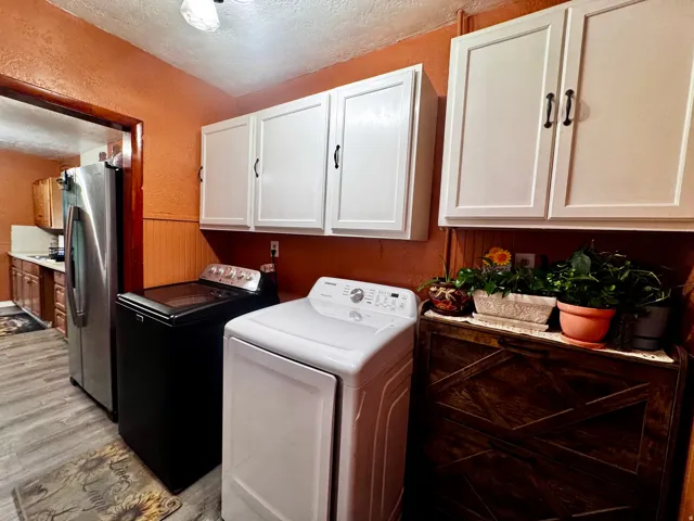 Wood-finish flooring with white overhead cabinetry and a built-in wood-paneled wall