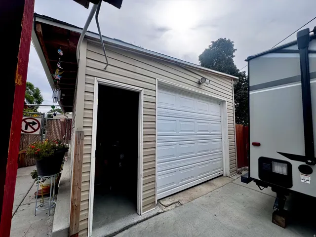 Single-car garage with a paneled door, light-toned siding, and an exterior light fixture